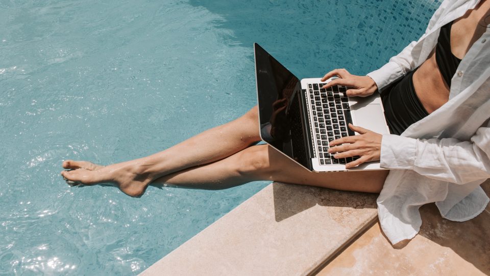 woman sitting on the edge of a pool with a laptop at The Legacy at Veramendi